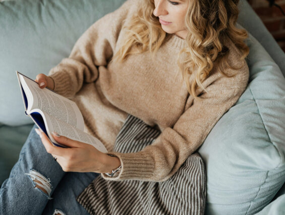 Eine Person liest gemütlich ein Buch auf dem Sofa im the salt Hallein.