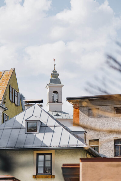Historic buildings with a steeple and traditional architecture under a cloudy sky in Hallein.