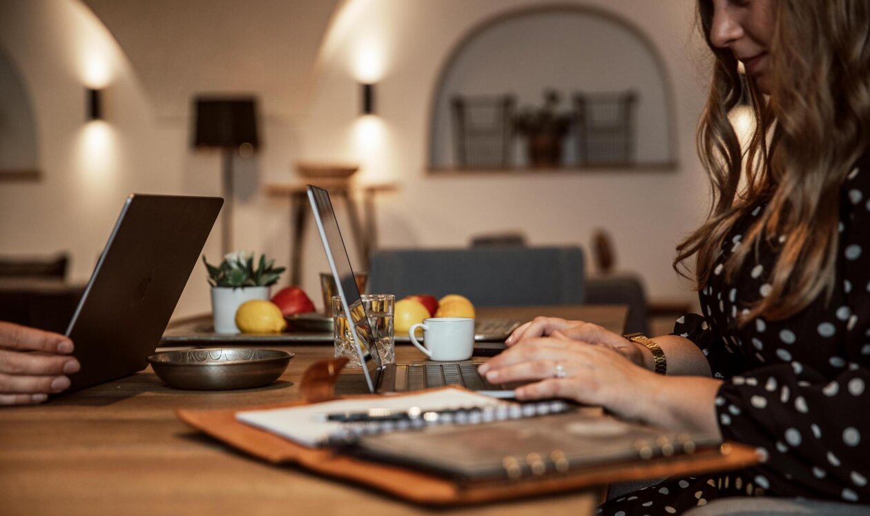 Eine Frau arbeitet an einem Laptop im Veranstaltungsraum im the salt townhouse mit warmem Licht und Dekoration.
