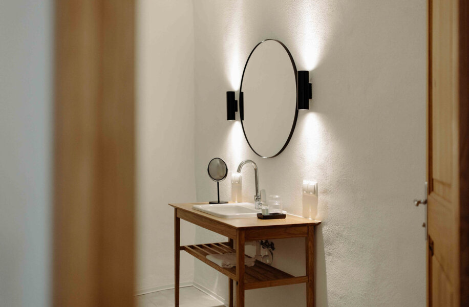 Badezimmer mit stilvollem Waschtisch und beleuchtetem Wandspiegel.