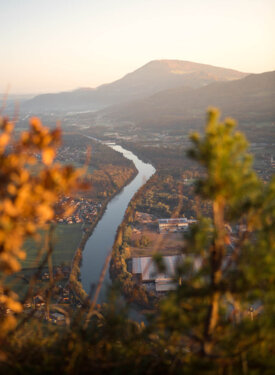 Blick auf die Salzach bei Hallein und umliegende Berge bei Sonnenuntergang, umgeben von Herbstlaub.