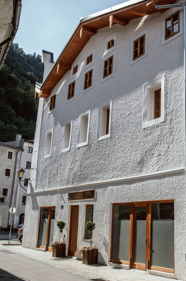 Außenansicht von the salt residences, mit weißer Fassade und Holzfenstern, im Sonnenlicht.