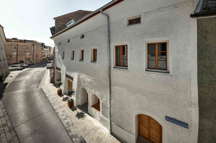 Historic street scene in Hallein, Austria, showing traditional architecture with white facades and wooden windows under a clear sky.