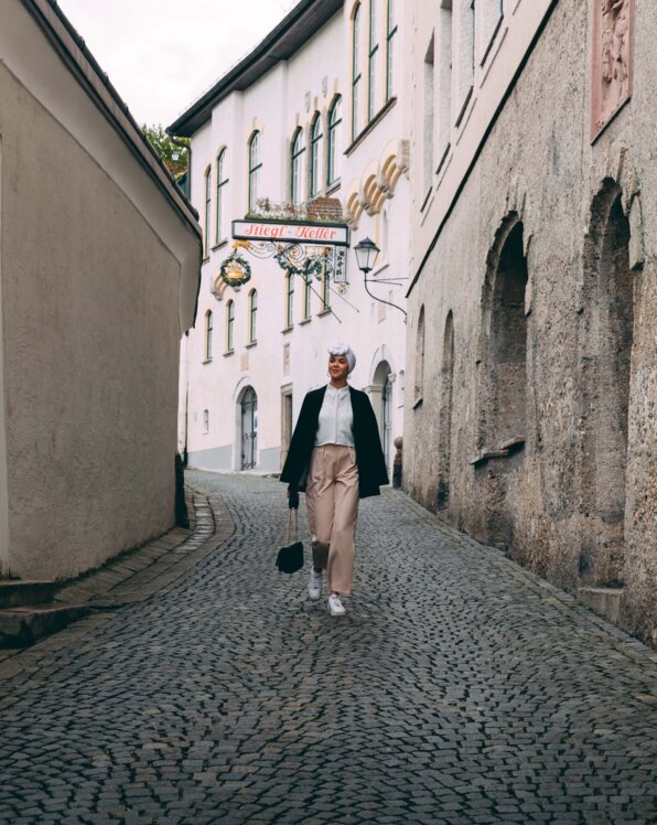 A person walks along a cobblestone lane between historic facades, capturing the old-town atmosphere.