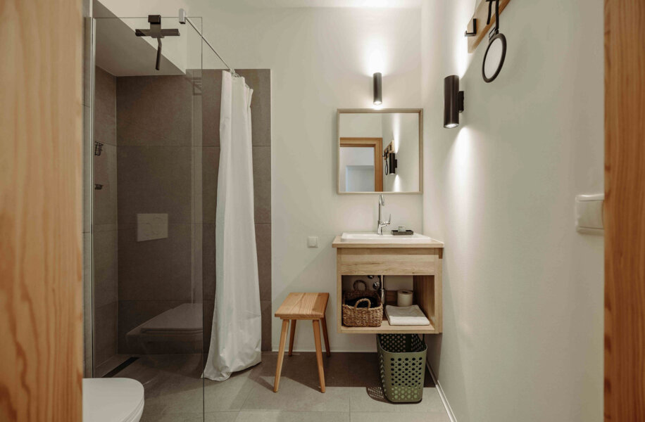Modernes Badezimmer mit begehbarer Dusche, Holzmöbeln und Spiegel.