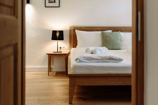 Gemütliches Schlafzimmer in einem stilvollen Apartment mit Holzbett, Nachttischlampe und moderner Dekoration.