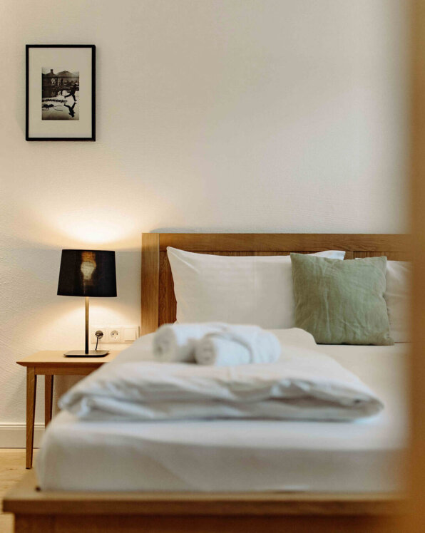 A cozy bedroom with a neatly made bed, soft lighting, and a side table lamp.