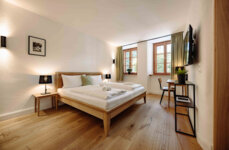 Gemütliches Schlafzimmer in stilvollem Apartment mit Doppelbett, Holzboden, TV und Schreibtisch.
