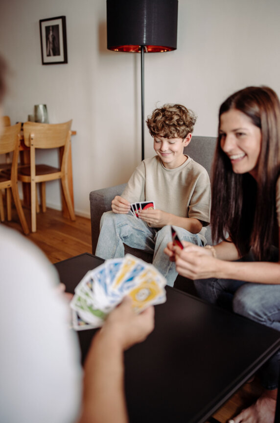 Family plays cards in the cozy apartment living room.