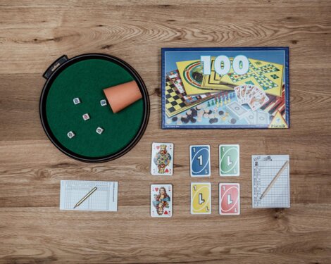 Brettspiele und Zubehör auf einem Holztisch, perfekt für gemütliche Abende in den stilvollen Apartments von the salt Hallein nahe Salzburg.