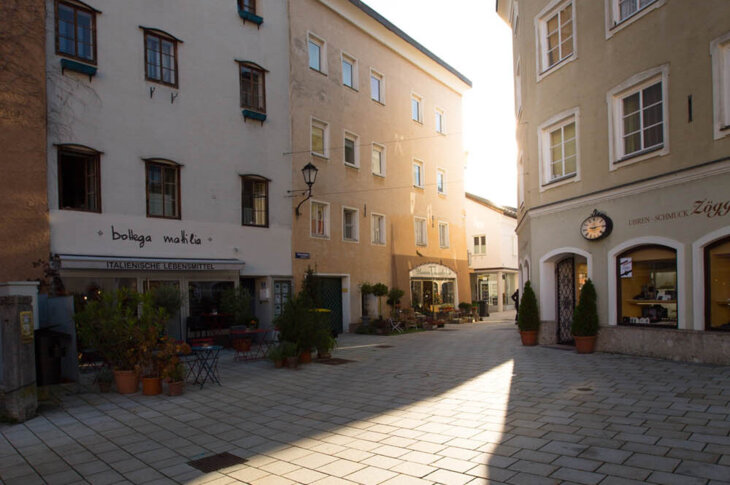 Ein sonniger Platz in Hallein, umgeben von traditionellen Gebäuden mit Geschäften und italienischem Restaurant.