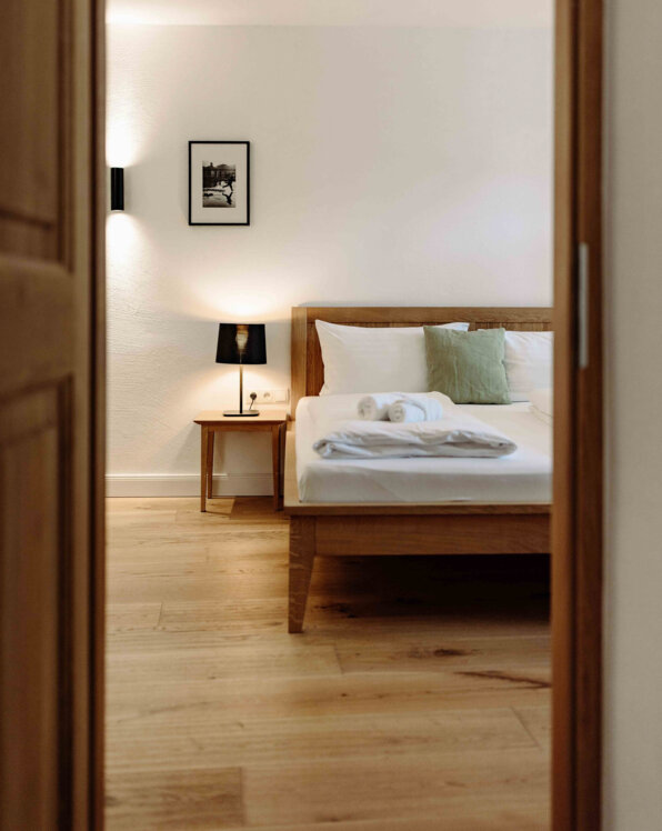 Gemütliches Schlafzimmer in einem stilvollen Apartment mit Holzbett, Nachttischlampe und moderner Dekoration.