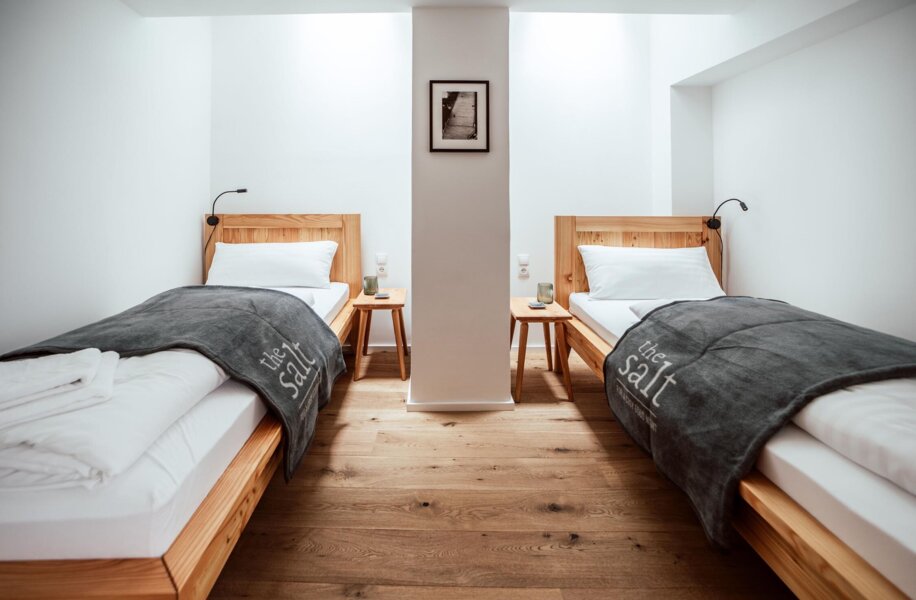 Gemütliches Schlafzimmer mit zwei Einzelbetten mit stilvollee Einrichtung mit Holzböden und minimalistischer Dekor.