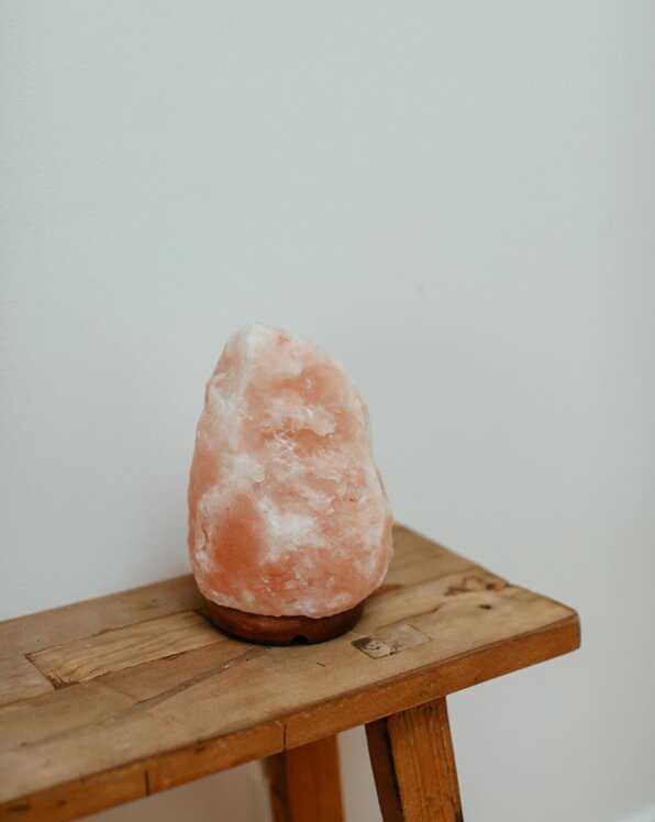 Ein rosa Salzstein auf einem Holzstuhl vor einer weißen Wand.