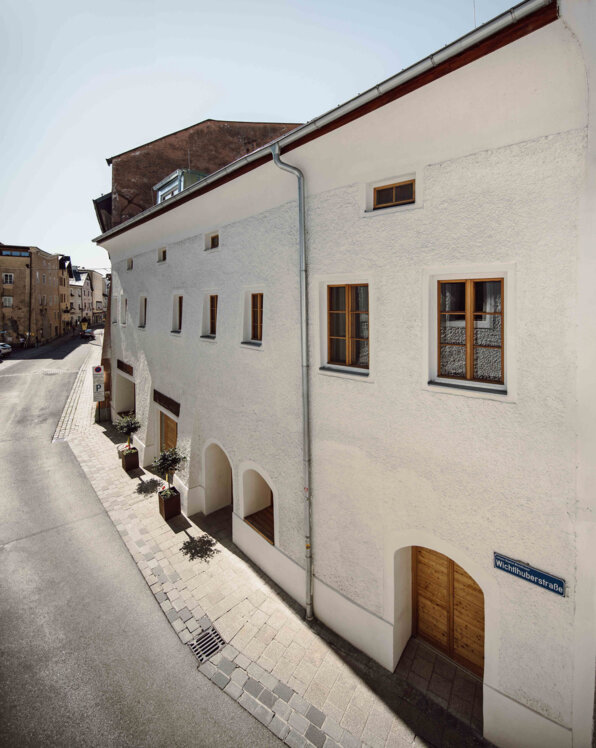 Außenansicht the salt in Hallein mit weißer Fassade und Holztüren bei Sonnenschein.
