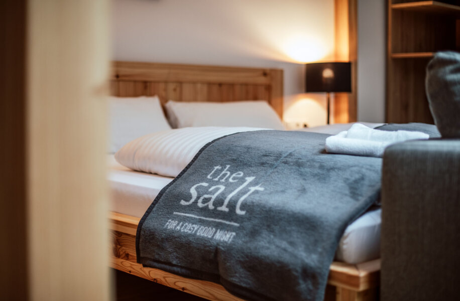 Cozy bedroom with wooden furniture, soft lighting, and a gray blanket on the bed labeled "the salt."
