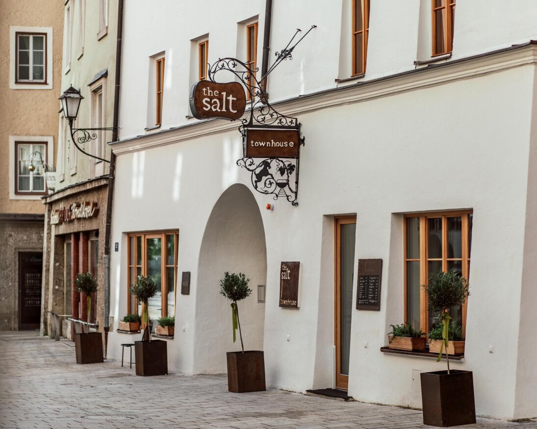 Stilvolle Fassade von "The Salt Townhouse" in Hallein, Salzburg, mit gemütlichen Fenstern und Pflanzen.
