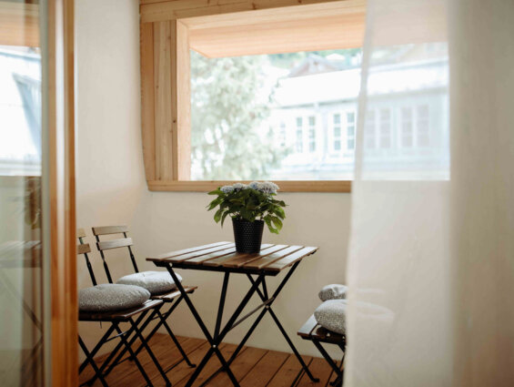 Balkon eines Apartments in Hallein bei Salzburg, ausgestattet mit Holzmöbeln und Blumendekor.