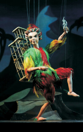 Eine bunte Marionette auf einer Bühne in einem stilvollen Theater.