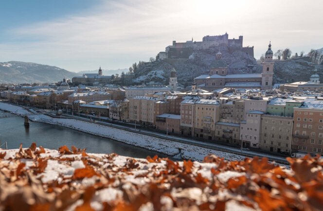 Snowy panorama of Salzburg with Hohensalzburg Fortress above the Salzach River.