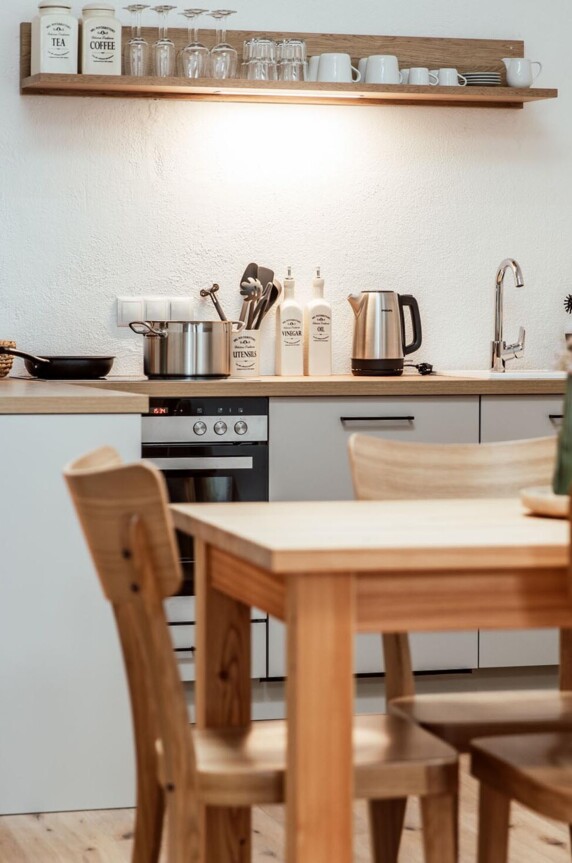 Voll ausgestattete Küche in einem the salt-Apartment mit Holzmöbeln und modernen Geräten.