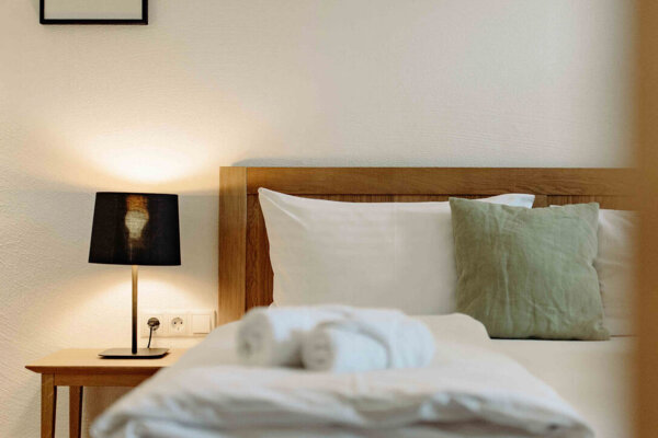 A cozy bedroom with a neatly made bed, soft lighting, and a side table lamp.