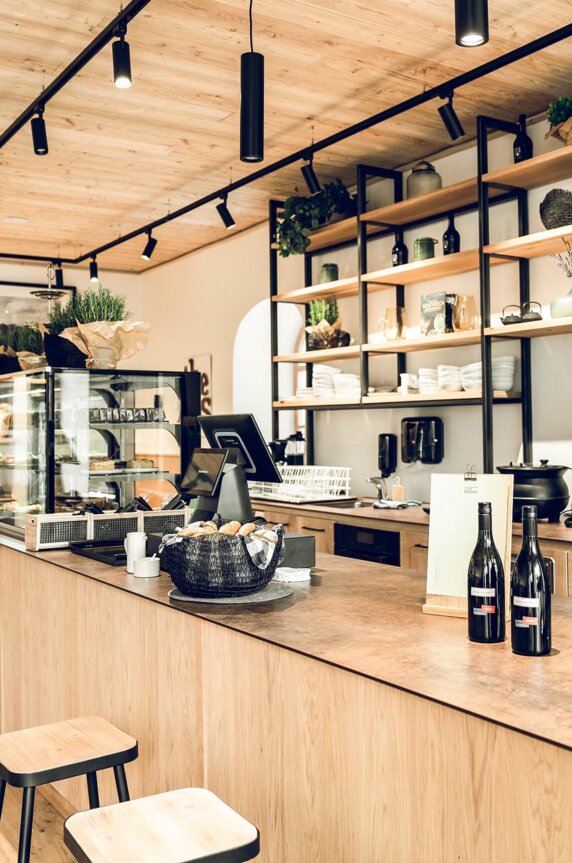 Helles Café - die Salzkrämerei - mit Holztheke, Siebträgermaschine, Vitrine und offenen Regalen.