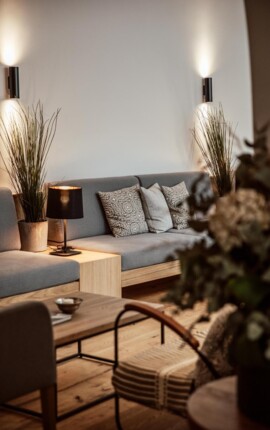 Gemütlicher Lounge-Bereich mit grauem Sofa, dekorativen Kissen, Pflanzen und stilvoller Beleuchtung im the salt townhouse. 
