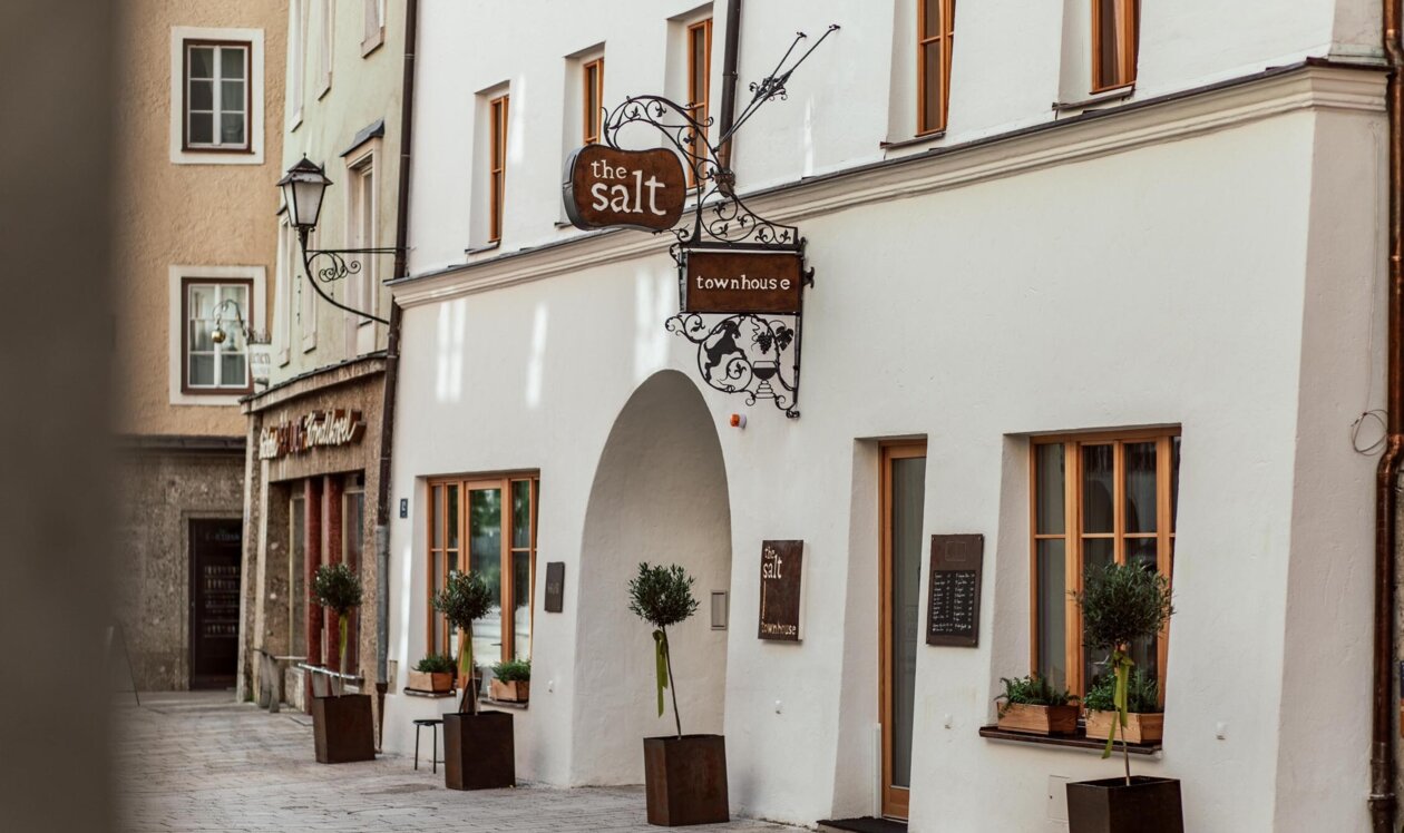 Stilvolle Fassade von "The Salt Townhouse" in Hallein, Salzburg, mit gemütlichen Fenstern und Pflanzen.