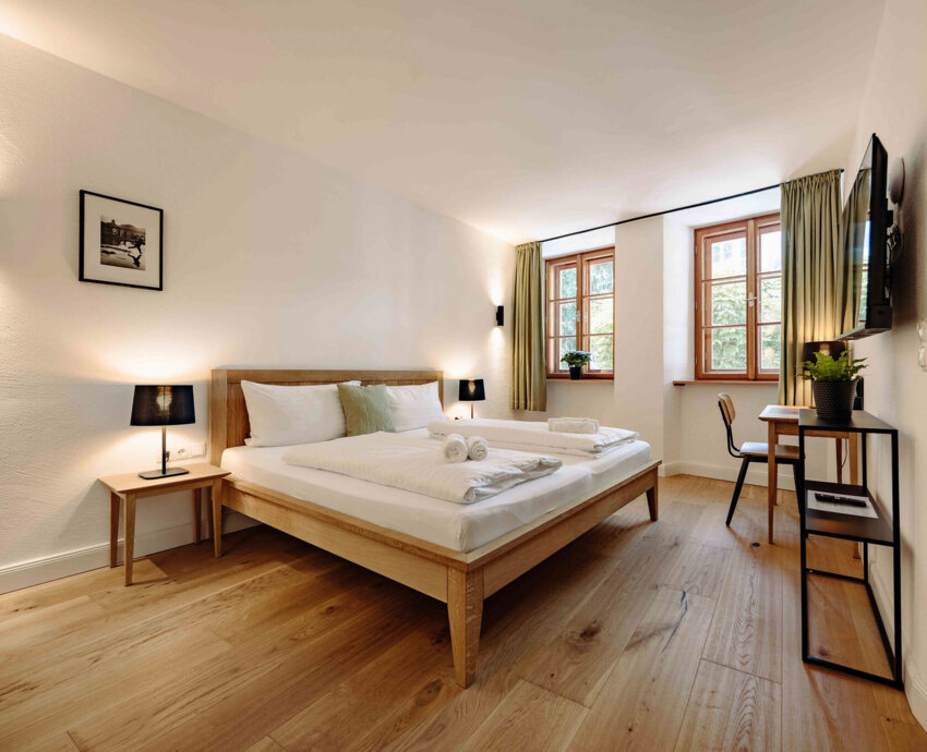 Gemütliches Schlafzimmer in stilvollem Apartment mit Doppelbett, Holzboden, TV und Schreibtisch.