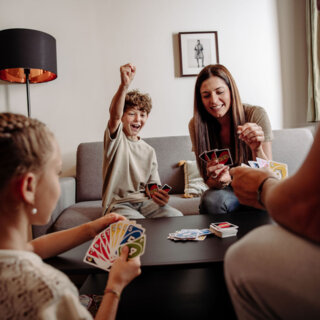 Familie mit zwei Kindern spielt UNO im Wohnbereich eines Zimmers von the salt Hallein.