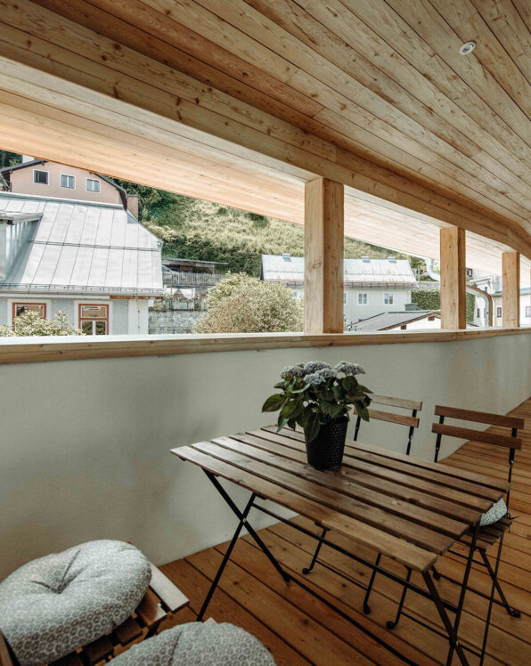 Großer, offener Holzbalkon mit Tisch und Stühlen im Galerie-Apartment von the salt Hallein.