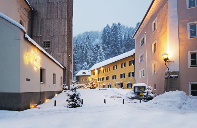 Winterliche Szene mit schneebedeckten Gebäuden in Hallein, beleuchtet mit warmen Lichtern.
