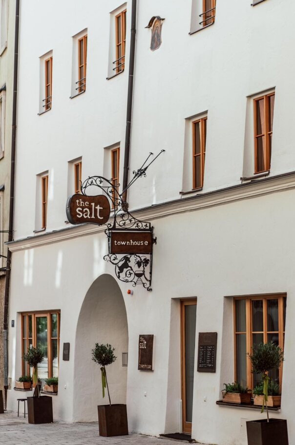 Facade of the salt townhouse in Hallein with arch entrance, wooden windows, and decorative sign.