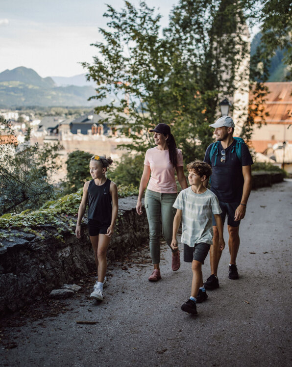 Familie spaziert auf einem Weg mit Blick über Hallein und die Berge.