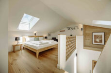 Schlafzimmer im Galerie-Apartment mit Dachfenster, gemütlichem Holzboden und moderner Einrichtung bei The Salt Hallein, Salzburg.