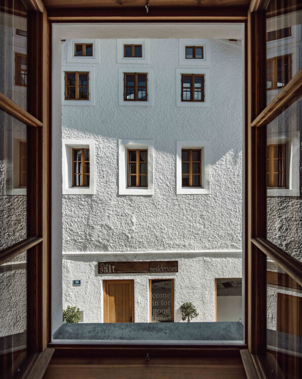 Blick aus einem Fenster auf the salt residences mit Holzfenstern. Ein Schild über der Tür weist auf "the salt residences" hin.