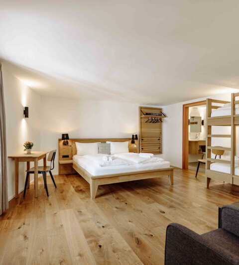 Gemütliches Apartment in Salzburg mit Doppelbett, Etagenbett, und Holzfußboden, ideal für Familienurlaub.