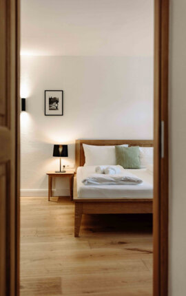 Gemütliches Schlafzimmer in einem stilvollen Apartment mit Holzbett, Nachttischlampe und moderner Dekoration.
