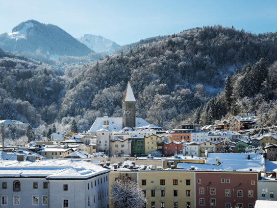 Hallein im Winter mit bunten Häusern und schneebedeckten Bergen im Hintergrund.