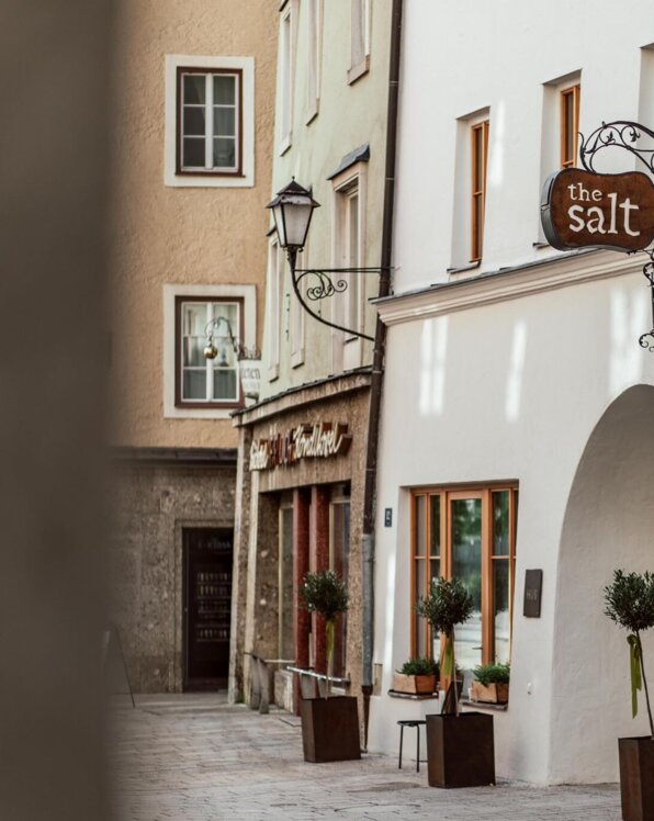Stilvolle Fassade von "The Salt Townhouse" in Hallein, Salzburg, mit gemütlichen Fenstern und Pflanzen.