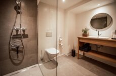 Stilvolles Badezimmer mit moderner Dusche, WC und Holzwaschtisch.