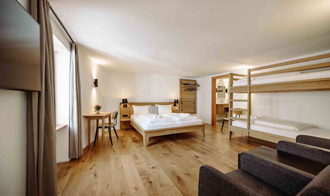 Gemütliches Apartment in Salzburg mit Doppelbett, Etagenbett, und Holzfußboden, ideal für Familienurlaub.