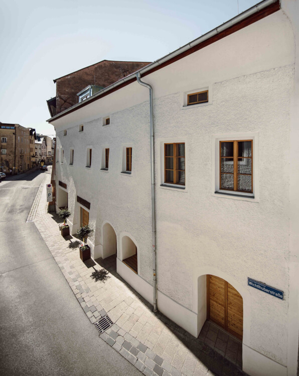 Außenansicht the salt in Hallein mit weißer Fassade und Holztüren bei Sonnenschein.