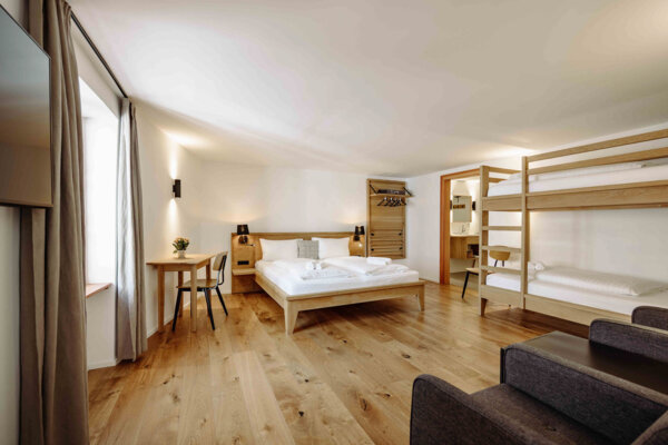 Gemütliches Apartment in Salzburg mit Doppelbett, Etagenbett, und Holzfußboden, ideal für Familienurlaub.