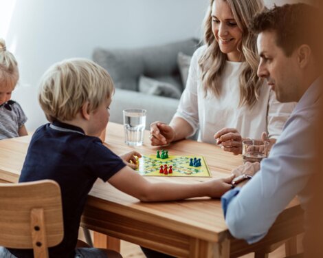 Familie spielt Brettspiel am Holztisch in gemütlicher, stilvoller Wohnung.