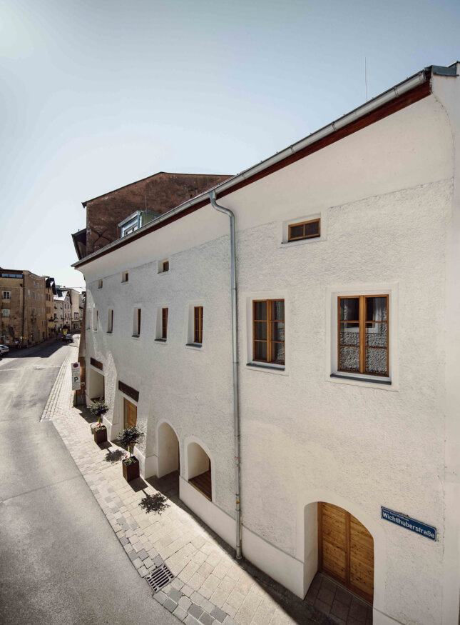 Außenansicht the salt in Hallein mit weißer Fassade und Holztüren bei Sonnenschein.