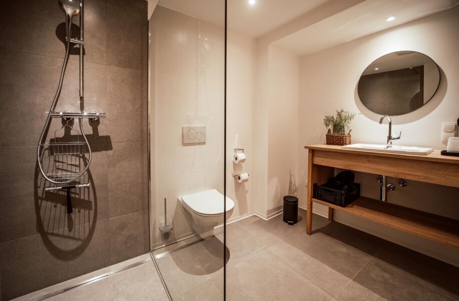 Stilvolles Badezimmer mit moderner Dusche, WC und Holzwaschtisch.