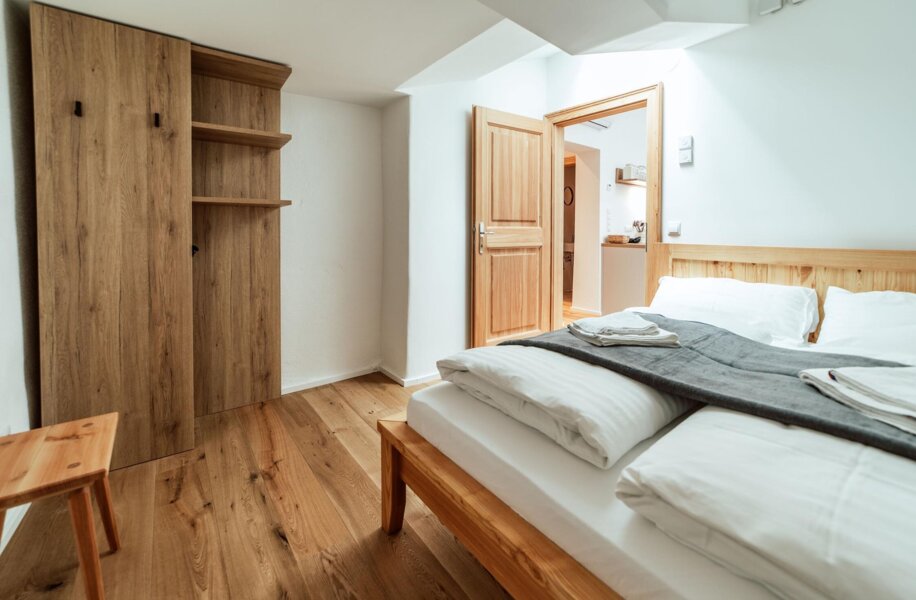 Schlafzimmer mit Holzboden, Doppelbett und Kleiderschrank, ideal für einen längeren Aufenthalt.