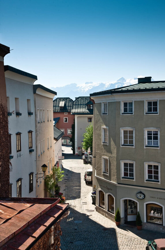 Straßenszene in Hallein mit historischen Gebäuden und Bergen im Hintergrund bei klarem Himmel.